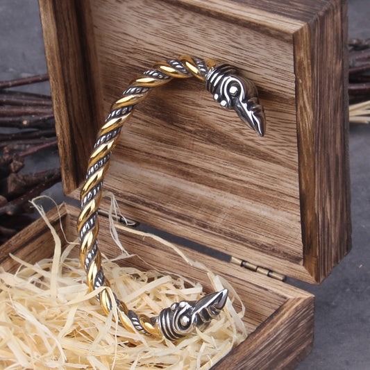 Mixed silver and gold torq bracelet featuring symbolic raven heads, a stylish and adjustable piece inspired by Norse mythology.